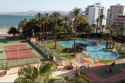 a resort with two pools and a tennis court at NUEVO, primera linea de playa, con piscina y vistas al mar in Cullera