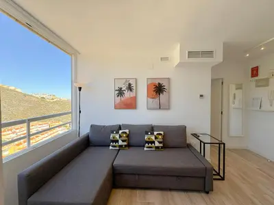 a living room with a couch and a large window at NUEVO, primera linea de playa, con piscina y vistas al mar in Cullera