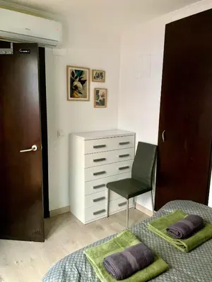 a bedroom with two beds and a chair and a dresser at Cosy and Modern Puerto de Sagunto Holiday Flat in Puerto de Sagunto