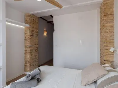 a bedroom with a white bed and a brick wall at Beautiful restored house with terrace in Valencia