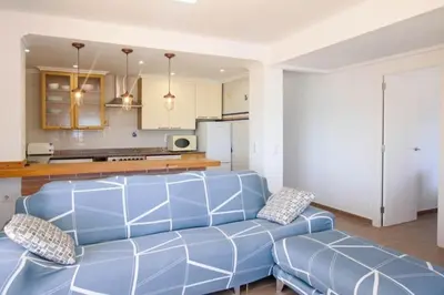 a living room with a blue couch and a kitchen at The perfect holiday apartment with fantastic views in Faro de Cullera
