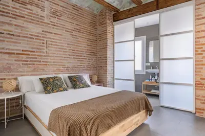 a bedroom with a bed and a brick wall at Céntrica y encantadora vivienda. in Valencia