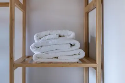 a stack of towels on a wooden shelf in a bathroom at Céntrica y encantadora vivienda. in Valencia