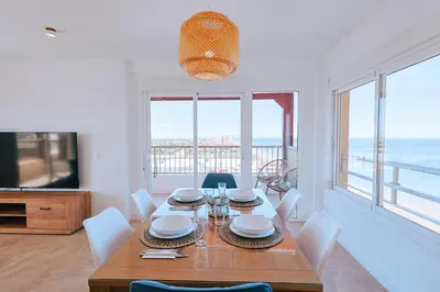a dining room with a table and chairs and a television at Apartamento prémium con 5 Piscinas Barbacoa Tenis Frontenis in Mareny Blau