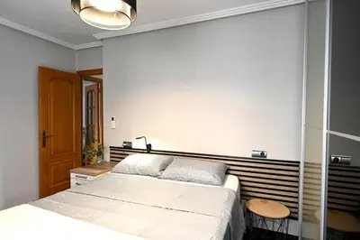 a bedroom with a large white bed and a wooden headboard at Playa Bonita Apartment in Puerto de Sagunto