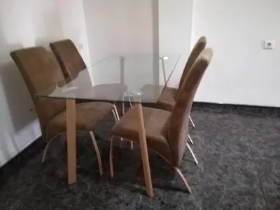 a glass table with four brown chairs around it at Mi playa in Puerto de Sagunto