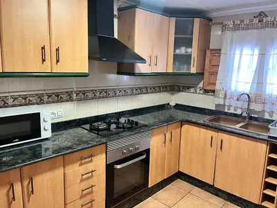 a kitchen with wooden cabinets and a stove top oven at Villas de descanso in Vilamarxant