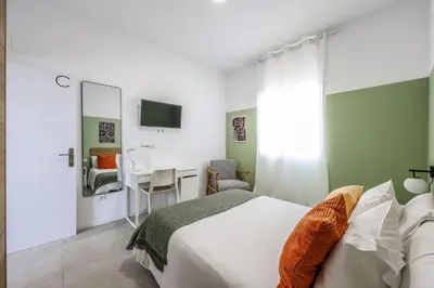 a bedroom with a bed and a chair and a tv at AmazINN Places Valencia Cabanyal in Valencia