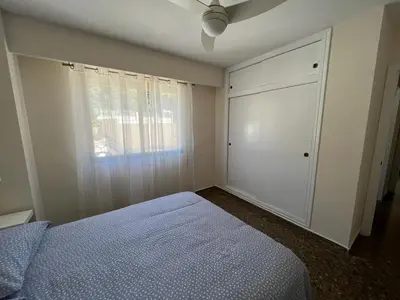 a bedroom with a blue bed and a window at Apartamento familiar en Cullera - Playa el Racó in Cullera