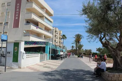 a building with people sitting on a sidewalk next to a building at TBC The Beach Corner in Canet de Berenguer