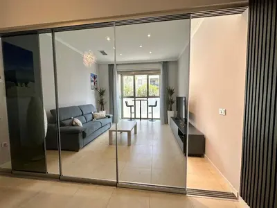 a living room with a couch and a glass wall at Reinapart Patacona Beach 36 in Valencia