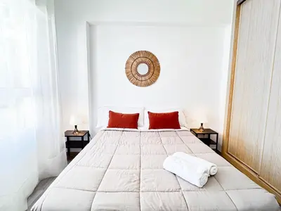 a white bedroom with a large white bed with red pillows at NUEVO, a 50 metros de la playa y con vistas al mar in Cullera