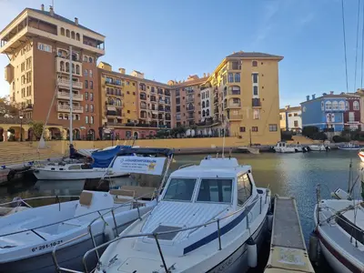 a boat is docked in a marina with buildings at Port Saplaya 3 habitaciones Valencia in Port Saplaya