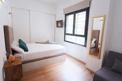 a white bedroom with a bed and a mirror at Lujoso Hogar cerca del Casco Antiguo de la ciudad in Valencia