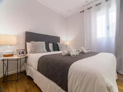 a white bedroom with a large bed and a table at MD Iturbi Jardin Turia in Valencia