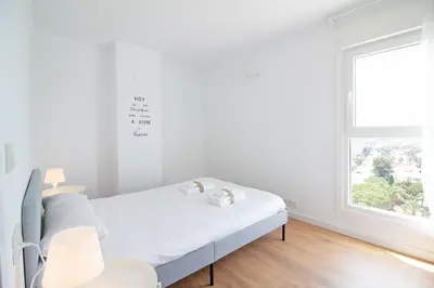 a white bedroom with a bed and a window at Global Vacacional, Apartamento con terraza y vistas al mar in Canet de Berenguer