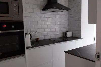 a white kitchen with a stove and a microwave at Santa Marta frente al mar in Cullera