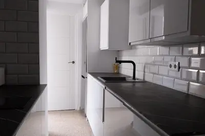 a kitchen with white cabinets and a black counter top at Santa Marta frente al mar in Cullera