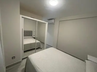 a small bedroom with a bed and a mirror at Apartamento de lujo en Cullera con Aire Acondicionado in Cullera