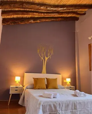 a bedroom with a bed with a tree painted on the wall at Casa rural La Boticaria in Villar del Arzobispo