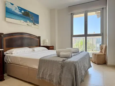 a bedroom with a bed and a chair and a window at Reinapart Patacona Beachfront Seaview in Valencia