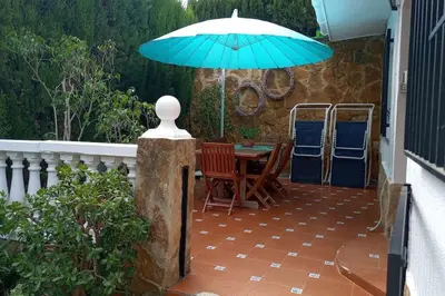 a patio with a table and a blue umbrella at Casa Tena in Partida de La Cañada