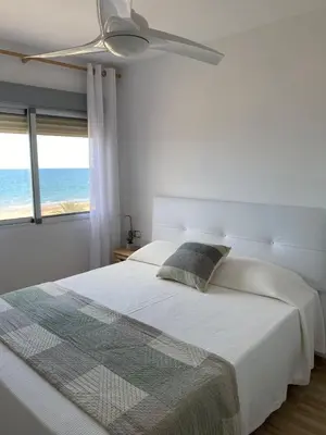 a white bedroom with a bed and a ceiling fan at Cara al mar in Cullera