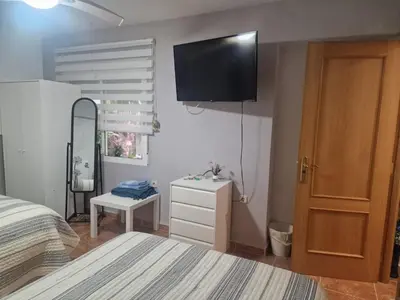 a bedroom with a bed and a television on the wall at Habitaciones Zoe in Puerto de Sagunto