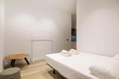 a white bedroom with a bed and a table at VLC HOST - Cubells in Valencia