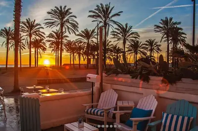 a patio with chairs and palm trees at sunset at Valencia Ático playa Patacona. Parking incluido in Valencia