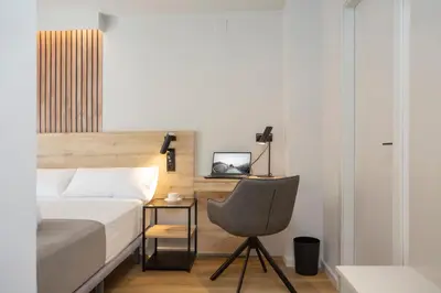 a bedroom with a bed and a chair and a desk at Aila II Hotel Boutique by SingularStays - Digital Access in Burjasot