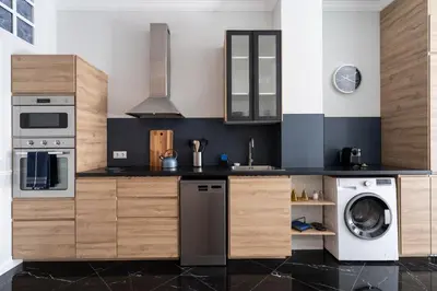 a kitchen with wooden cabinets and a washer and dryer at Le Parisien de COUP DE COEUR APPARTEMENTS in Valencia