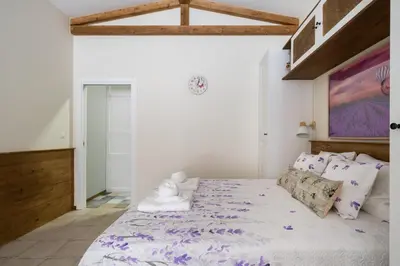 a white bedroom with a large bed with purple sheets at Le Provençal de COUP DE COEUR APPARTEMENTS in Valencia