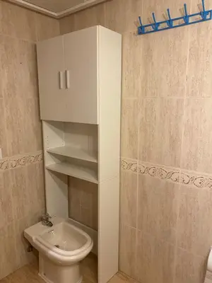 a white bathroom with a toilet and a cabinet at Apartamento frente al mar en Playa Patacona in Valencia