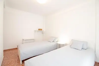 two beds in a room with white walls at Global Vacacional, Apartamento de 3 dormitorios en Sagunto in Sagunto