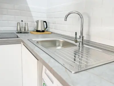 a stainless steel sink in a white kitchen at Global Vacacional, Apartamento con gran terraza en la playa de Canet in Canet de Berenguer