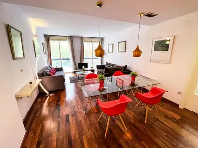 a living room with a glass table and red chairs at Baron Suites in Valencia