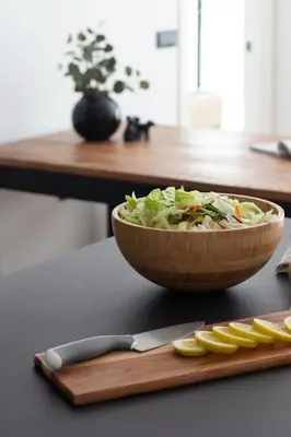 a bowl of salad on a table with a knife and lemon slices at VLC HOST - Duque de Gaeta in Valencia