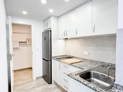 a kitchen with a sink and a refrigerator at NUEVO, a 60 metros de la playa y con vistas laterales al mar in Cullera