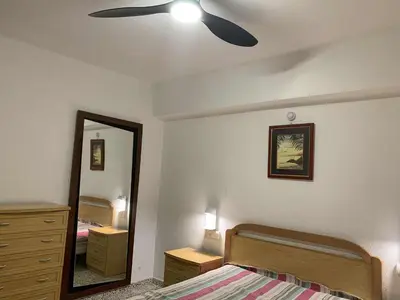 a bedroom with a ceiling fan and a bed and a mirror at RIU MAR Apartment Cullera in Cullera