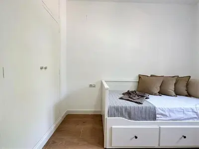 a white bed in a room with a white wall at Your Poolside Paradise by the Sea in Port Saplaya