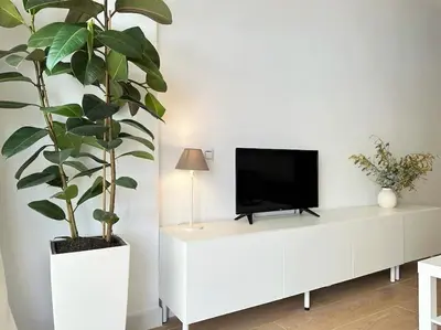 a white entertainment center with a tv and a plant at Your Poolside Paradise by the Sea in Port Saplaya