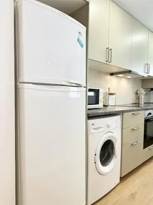 a kitchen with a refrigerator and a washing machine at Your Poolside Paradise by the Sea in Port Saplaya