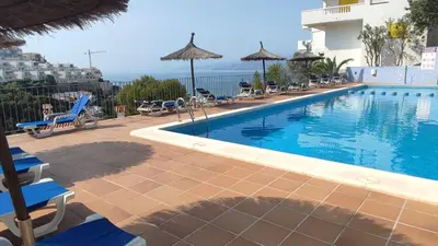 a pool with chairs and umbrellas next to a building at Una casa con vistas in Faro de Cullera
