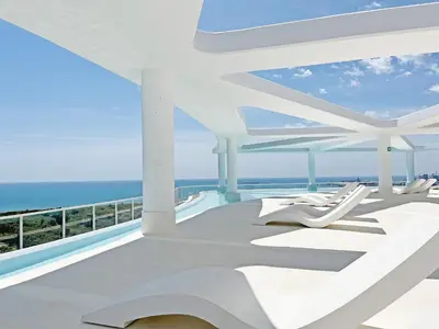 a balcony with white chairs and the ocean at Global Vacacional, Apartamento con terraza, vistas al mar y a la piscina in Canet de Berenguer