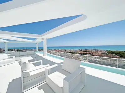 a balcony with white chairs and a view of the ocean at Global Vacacional, Apartamento con terraza, vistas al mar y a la piscina in Canet de Berenguer