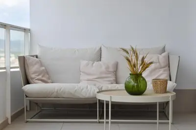 a white couch with a table and a vase on it at Global Vacacional, Moderno apartamento con terraza en Gran Canet in Canet de Berenguer