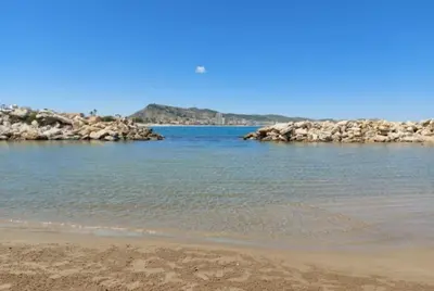 a sandy beach with rocks in the water at Terraced house in natural essence in Favareta