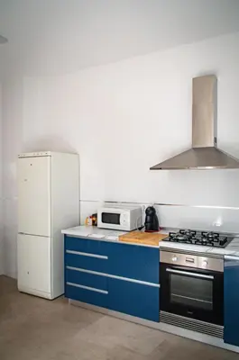 a kitchen with blue cabinets and a white refrigerator at Casa vacacional El Sol in Turís