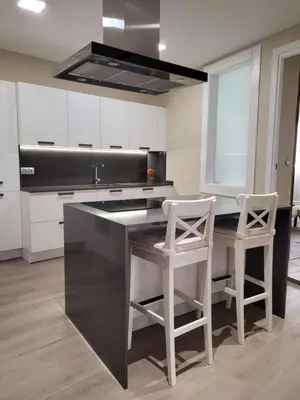 a kitchen with a black island and two white stools at La Casa Alandí con garaje privado in Sagunto